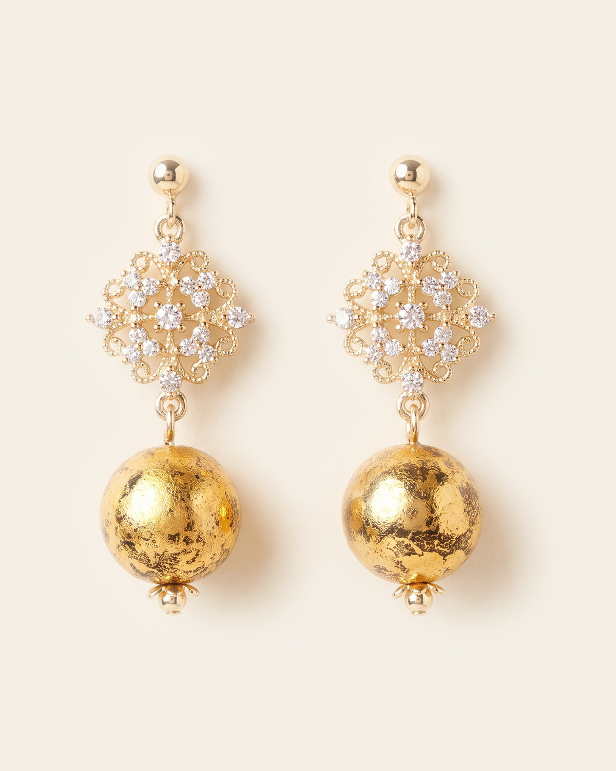 Pair of drop earrings with gold ball studs, filigree flowers set with clear stones and gold-leaf lacquer spheres, on an ivory background