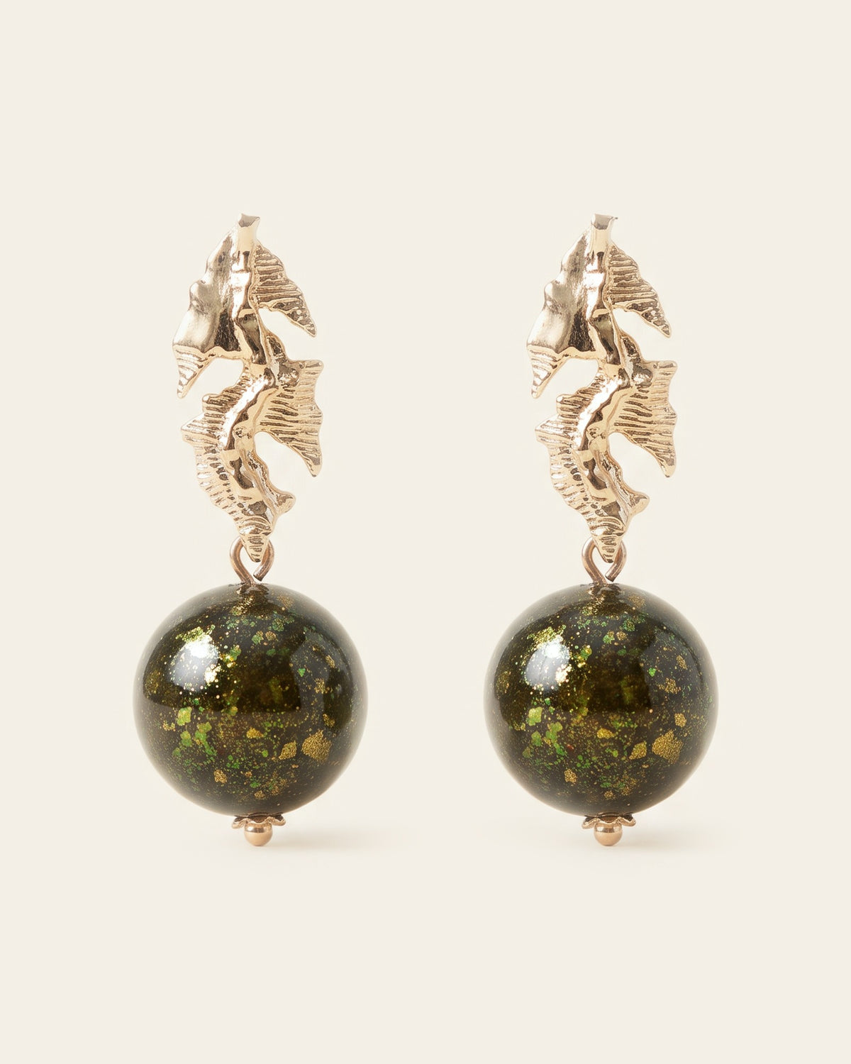 Pair of drop earrings with sculpted gold leaf studs and dark green lacquer spheres flecked with green and gold, on an ivory background