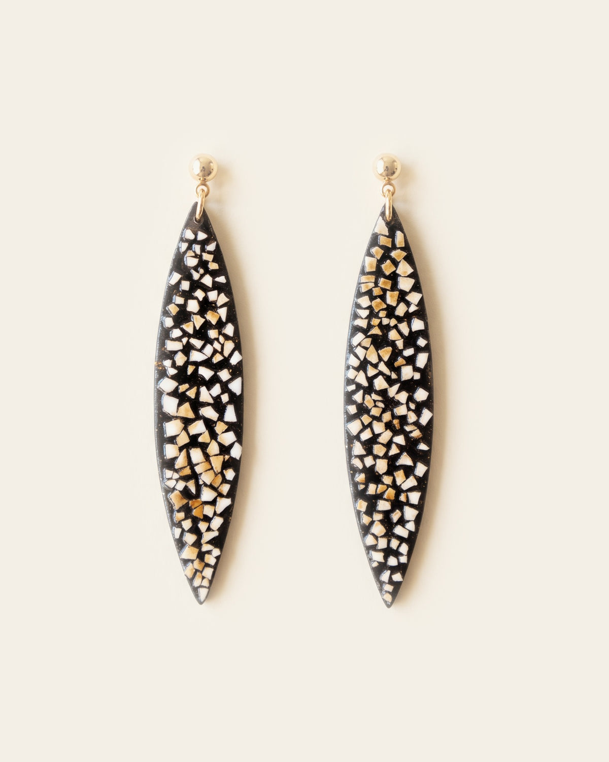 Pair of long black lacquer leaf-shaped drop earrings with ivory duck eggshell inlay, hanging from small gold ball studs on an ivory background