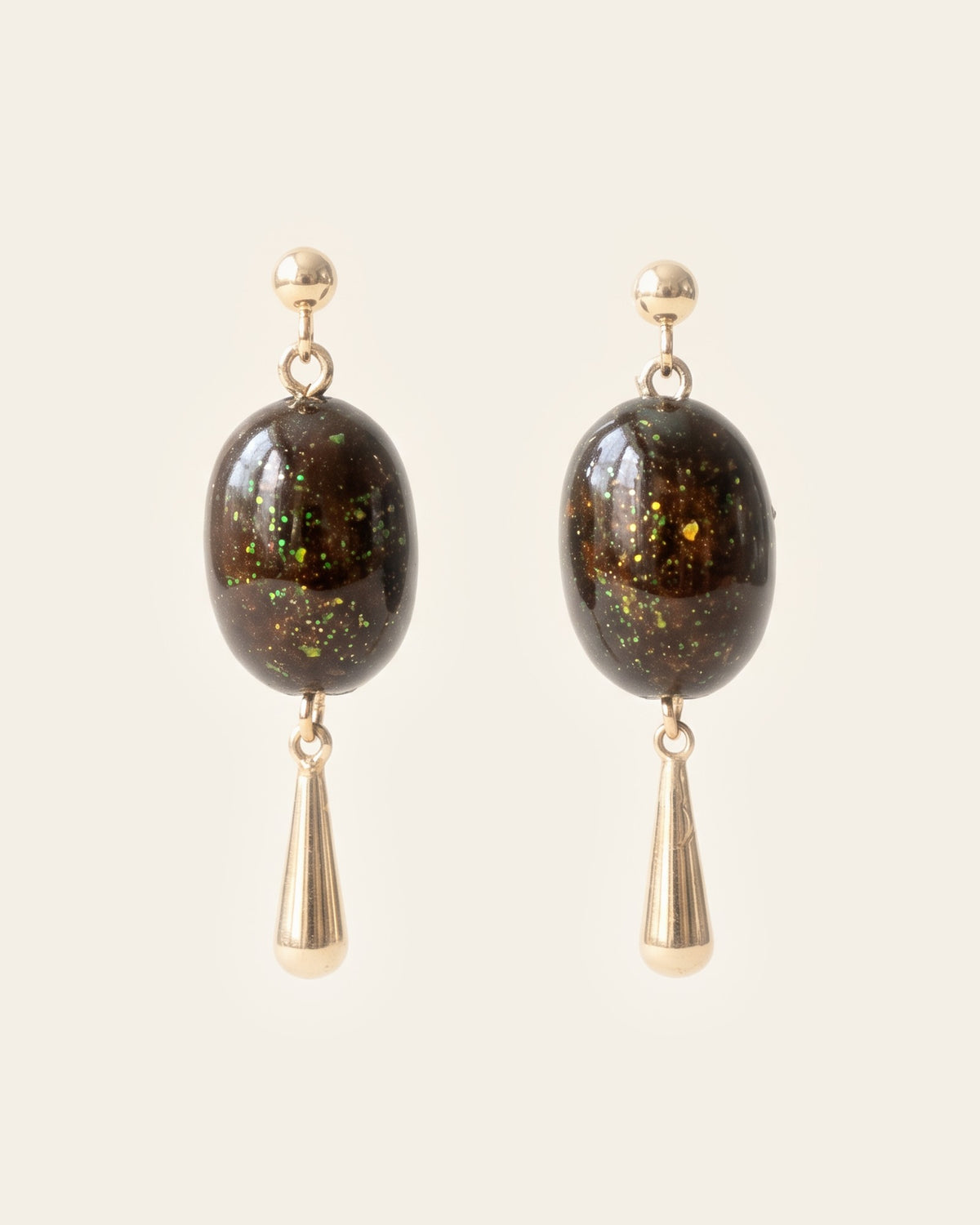Pair of drop earrings with gold ball studs, deep brown gold-flecked lacquer oval beads and slim gold teardrops, on an ivory background